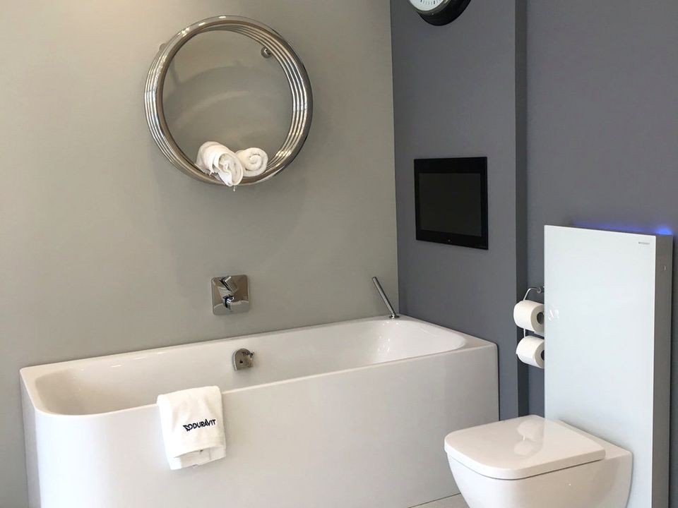 Duravit bath with a chrome towel rail and round mirror above